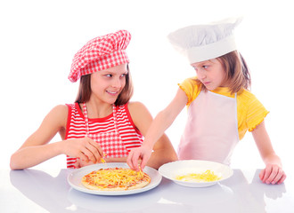 Two kids dressed as chefs preparing a pizza - isolated