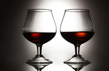 Two glasses of cognac on grey background