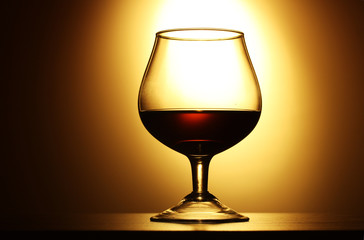 Glass of cognac on yellow background