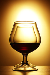 Two glasses of cognac on yellow background