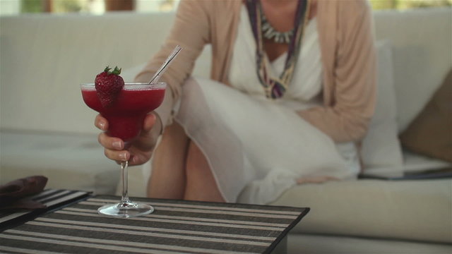 Woman sitting in bar and drinking strawberry cocktail