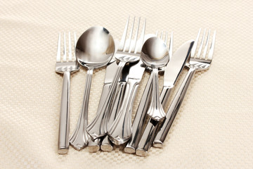 Forks, spoons and knives on a beige tablecloth