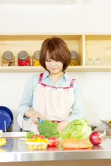 Beautiful young woman in kitchen making salad