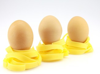 trois oeufs posés sur des nids de tagliatelle