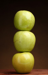 juicy green apples on wooden table on brown background