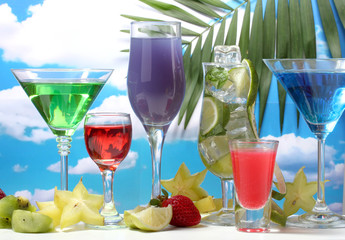 Glasses of cocktails on table on blue sky background