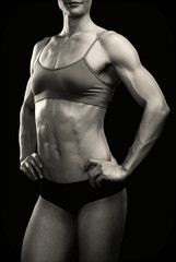 Fototapeta na wymiar Female fitness bodybuilder posing against black background