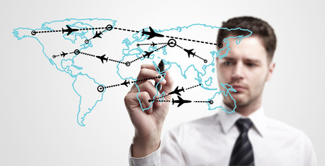 Young business man drawing an airplane routes on world map