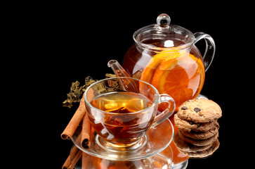 Glass teapot and cup with black fruit tea and cookies isolated