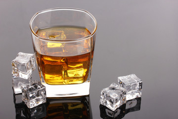 glass of scotch whiskey and ice on grey table