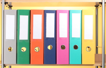 bright office folders on wooden shelf on yellow background