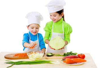 Two smiling kids preparing salad