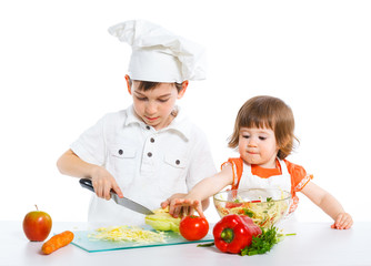 Two smiling kids mixing salad