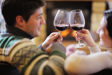Young romantic couple sitting on sofa in front of fireplace at h