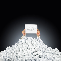 Person under crumpled pile of papers with hand holding a help si - obrazy, fototapety, plakaty