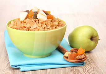 tasty cornflakes in bowl with dried fruits and apple