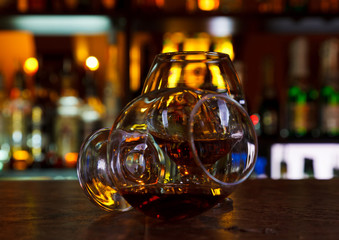 two glasses of brandy on a dark wooden table