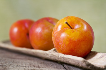 three yellow plums on wood