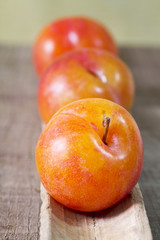 three yellow plums on wood
