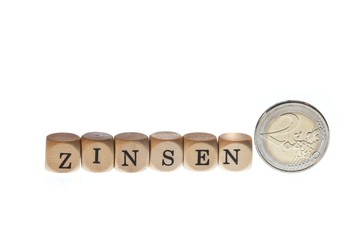 Wort "Zinsen" aus Buchstabenw&uuml;rfeln und Euro-M&uuml;nze, freigestellt, Freisteller