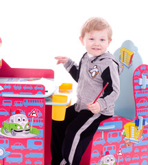 Baby boy with color pencils on child's chair