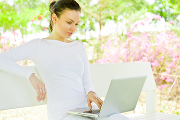 Businesswoman sitting on bench working on laptop in park