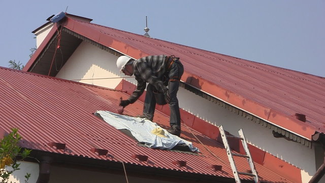Man paints roof of a private house