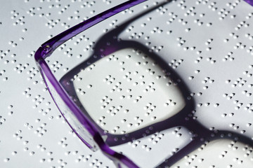 Brille und Buch in Blindenschrift. Braille
