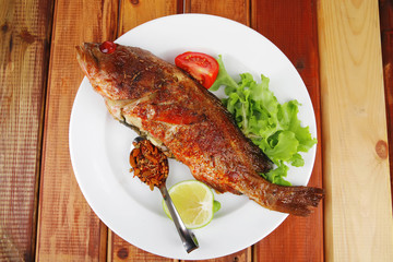 savory on wood: fried fish served with tomatoes