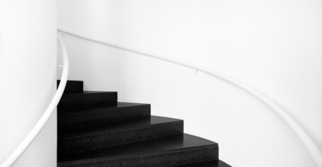 Spiral staircases between white walls and black floor