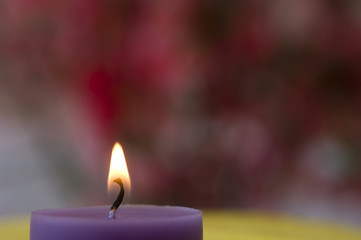 A purple candle in front of pink backround