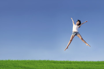 Excited woman jumping over blue sky