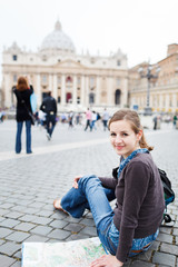 Fototapeta premium Pretty young female tourist studying a map at St. Peter's square