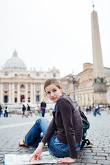 Pretty young female tourist studying a map at St. Peter's square