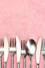 Forks, spoons and knives on a pink tablecloth