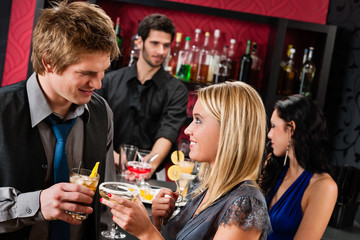 Happy friends at cocktail bar enjoy drinks