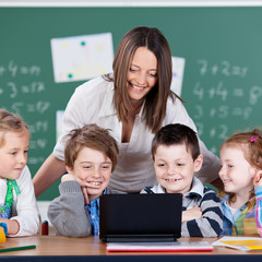 schüler und lehrerin schauen auf laptop