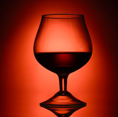 Glass of cognac on red background