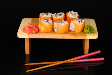 Tasty rolls served on wooden plate isolated on black