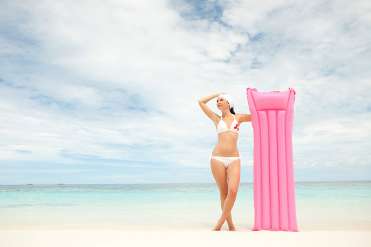 Happy woman with inflatable mattress on the beach
