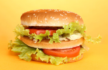 Big and tasty hamburger on yellow background