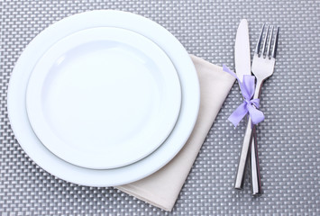 White empty plates with fork and knife tied with a ribbon