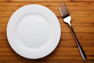 Empty plate and fork on wood table