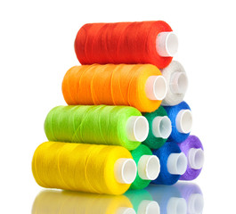 Pyramid of many-coloured bobbins of thread isolated on white
