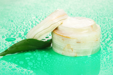 Opened jar of cream with fresh green leaf