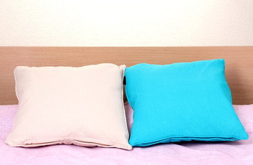 Fototapeta na wymiar bright pillows on bed on beige background