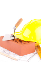 brick, yellow hard hat, tools and construction plans