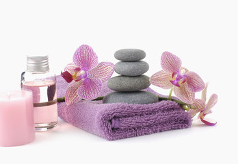 Stones on pink spa towels and beautiful orchid with massage oil