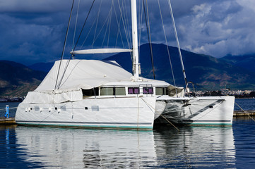 Fototapeta premium Sailing catamaran morred. Heavy sky background and reflections