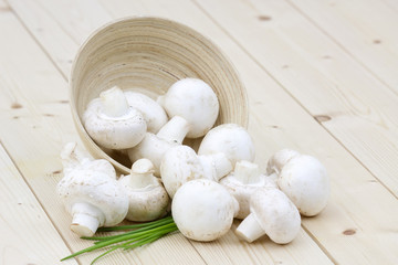 Fototapeta na wymiar mushrooms champignon scattered from a wooden bowl